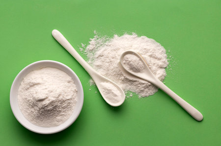 Baking soda - Crystalline solid compound in spoon and bowl. green background