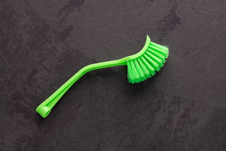 Plastic brush with green bristles for home cleaning.
