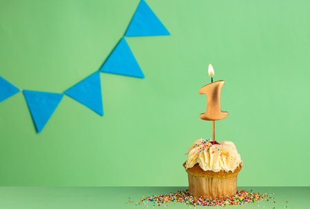 Birthday card with number 1 candle - Cupcake on a green background with blue pennants.の写真素材