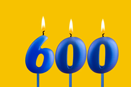Blue birthday candle on yellow background - Number 600の写真素材
