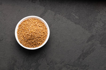 Yellow mustard seeds in bowl - Sinapis alba.の写真素材