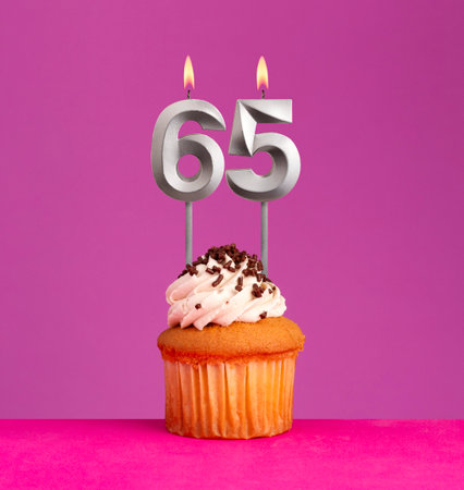 Birthday candle number 65 with cupcake on violet background.の写真素材