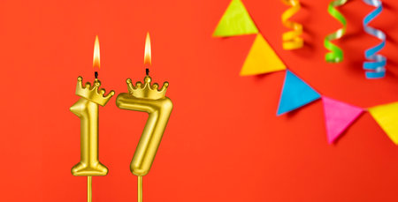 Number 17 birthday candle on an orange background with pennantsの写真素材