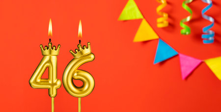 Number 46 candle - Birthday celebration on an orange background with pennants