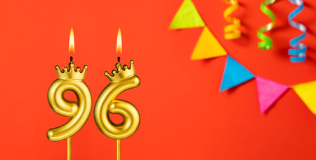 Number 96 candle - Birthday celebration on an orange background with pennantsの写真素材