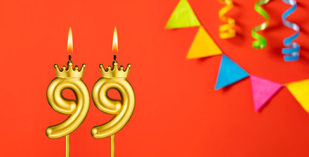 Number 99 birthday candle on an orange background with pennantsの写真素材