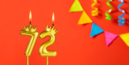 Number 72 candle - Birthday celebration on an orange background with pennantsの写真素材