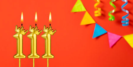 Number 111 birthday candle on an orange background with pennantsの写真素材