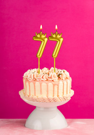 Number 77 birthday candle - Pink celebration cake with drip icingの写真素材