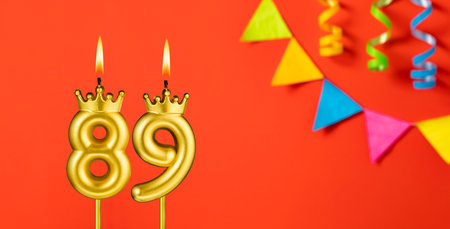 Number 89 birthday candle on an orange background with pennantsの写真素材