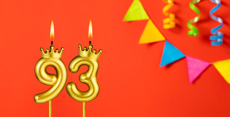 Number 93 birthday candle on an orange background with pennantsの写真素材