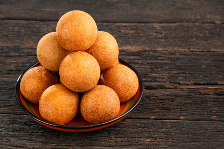 Fried cheese buÃ±uelos on a plate on a wooden background - Colombian foodの写真素材