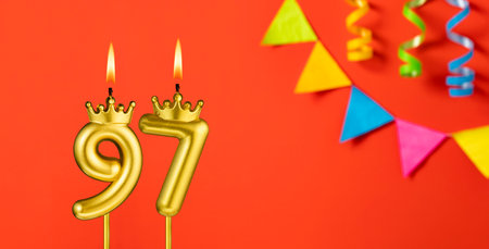 Number 97 birthday candle on an orange background with pennantsの写真素材