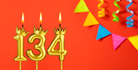 Number 134 candle - Birthday celebration on an orange background with pennantsの写真素材