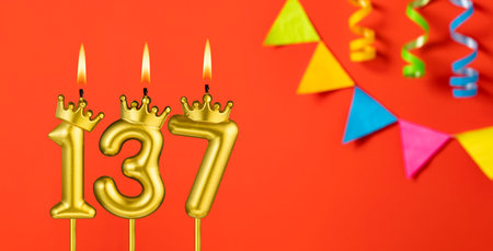 Number 137 birthday candle on an orange background with pennantsの写真素材