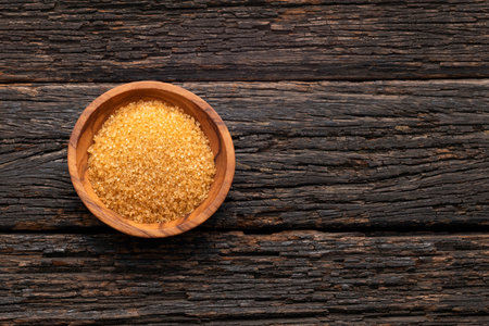 Organic brown sugar in a wooden bowl - Saccharum officinarumの写真素材