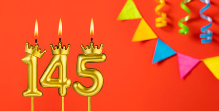 Number 145 birthday candle on an orange background with pennantsの写真素材