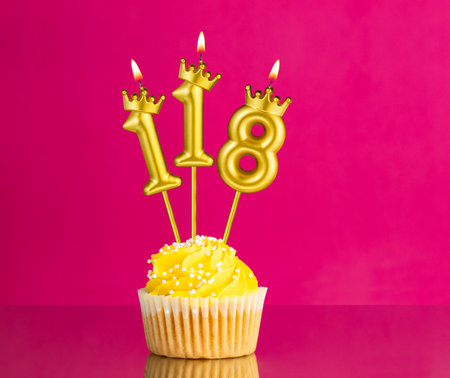 Birthday celebration with number 118 candle - Yellow cupcake on a pink backgroundの写真素材