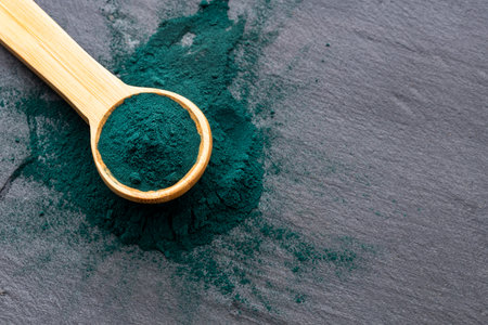Organic spirulina powder in the wooden spoon - Healthy foodの写真素材