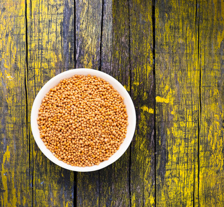 Dried and organic yellow mustard seeds in bowl - Sinapis alba.の写真素材