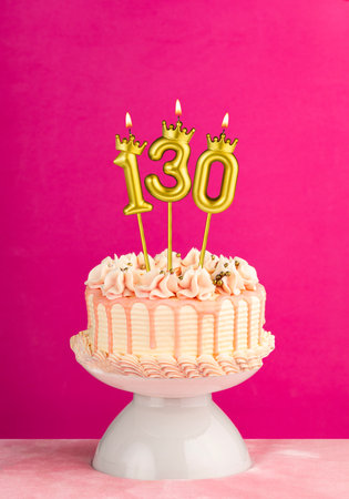 Pink birthday celebration cake with number 130 candleの写真素材