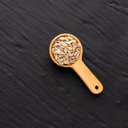 Raw and dried sunflower seeds in a spoon - Helianthus annuus.の写真素材
