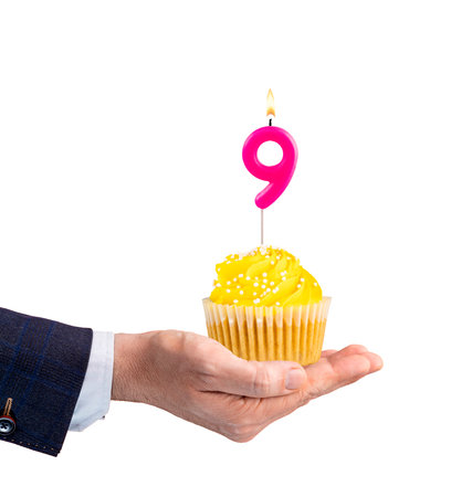 Hand holding a cupcake with a number 9 candle - Birthday on a white backgroundの写真素材
