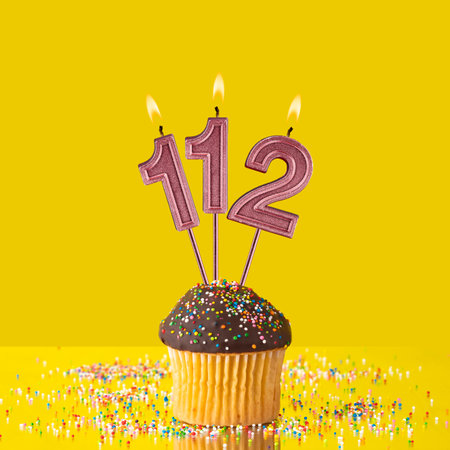 Birthday on a yellow background - Number 112 candleの写真素材