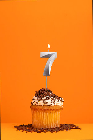 Birthday candle number 7 - Invitation card with orange background. cupcake