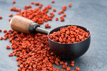 Bixa Orellana - Organic red annatto seeds on a spoon and scattered on the bottom