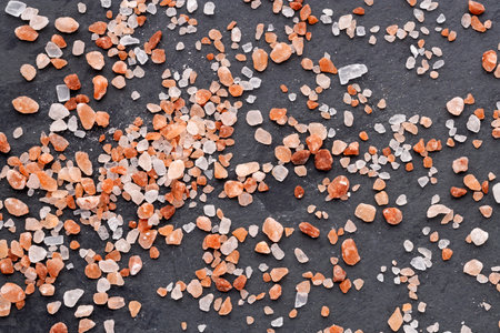 Pink Himalayan salt crystals scattered on a dark surfaceの写真素材