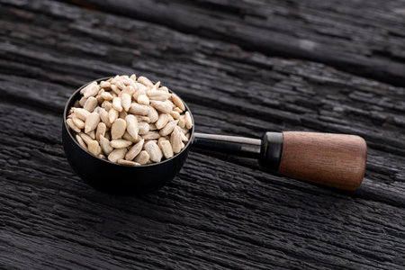 Shelled sunflower seeds in a metal and wooden spoon - Helianthus annuusの写真素材