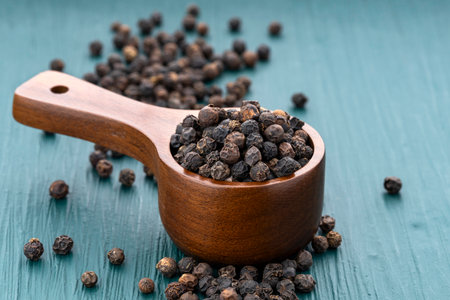Piper nigrum - Black peppercorns in a measuring spoon