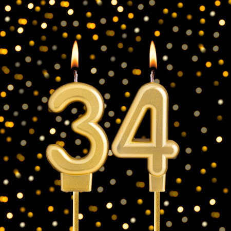 Number 34 birthday candle on a black background with blurred lights