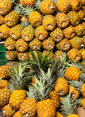 Pineapples for sale in a traditional Colombian market, highlighting the color, texture, and...