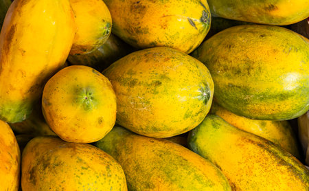 Ripe papayas displayed in a Colombian market, highlighting their yellow and green colors, natural...