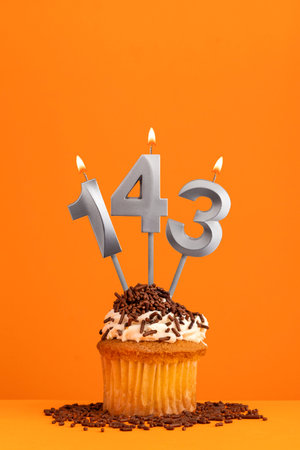Birthday candle number 143 - Invitation card with orange background. cupcake