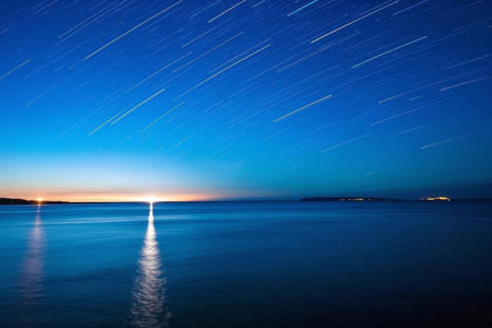 Tranquil sea under star tracks, starlight tracks under nightの素材