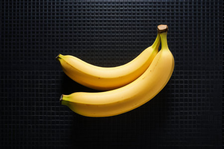 Two yellow bananas on a black backgroundの素材
