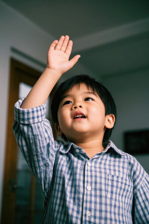 Cute baby raises hand to ask question with innocent eyesの素材