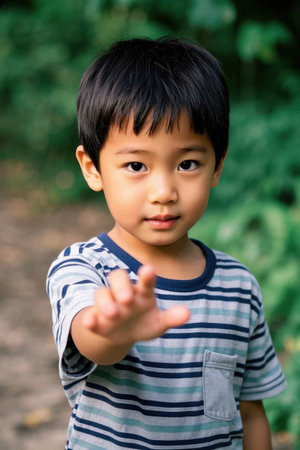 Cute boy sticking out his fingers outdoorsの素材