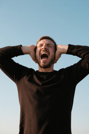 Man covers his ears and roars in the sky backgroundの素材