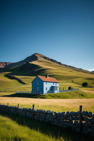 there is a blue house in a field with a mountain in the backgroundの素材
