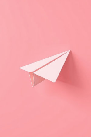 White paper airplane on pink backgroundの素材