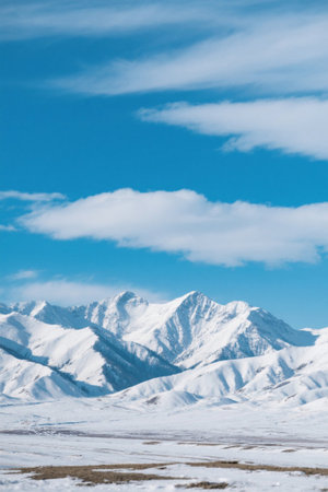 Panoramic view of snow-capped mountains under blue sky and white cloudsの素材