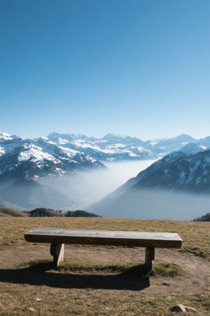 View of benches on the grass in front of the snow-capped mountainsの素材