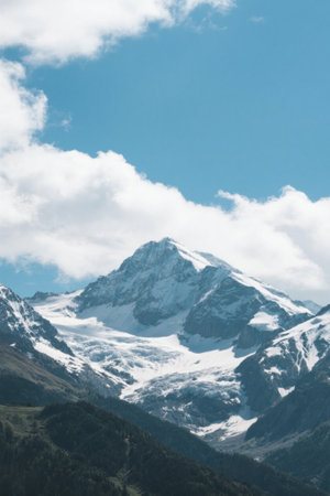 Snowy mountain scenery under blue sky and white cloudsの素材