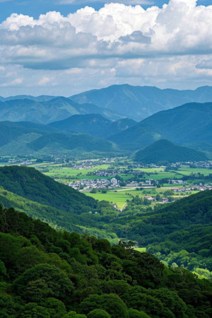 Panoramic view of the countryside amidst the mountains and green fieldsの素材