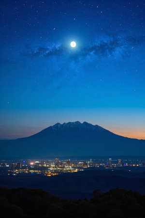 City and distant mountain landscape under moonlit nightの素材