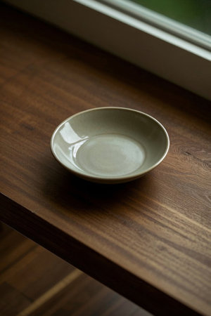 Light colored bowl on a wooden table by the windowの素材